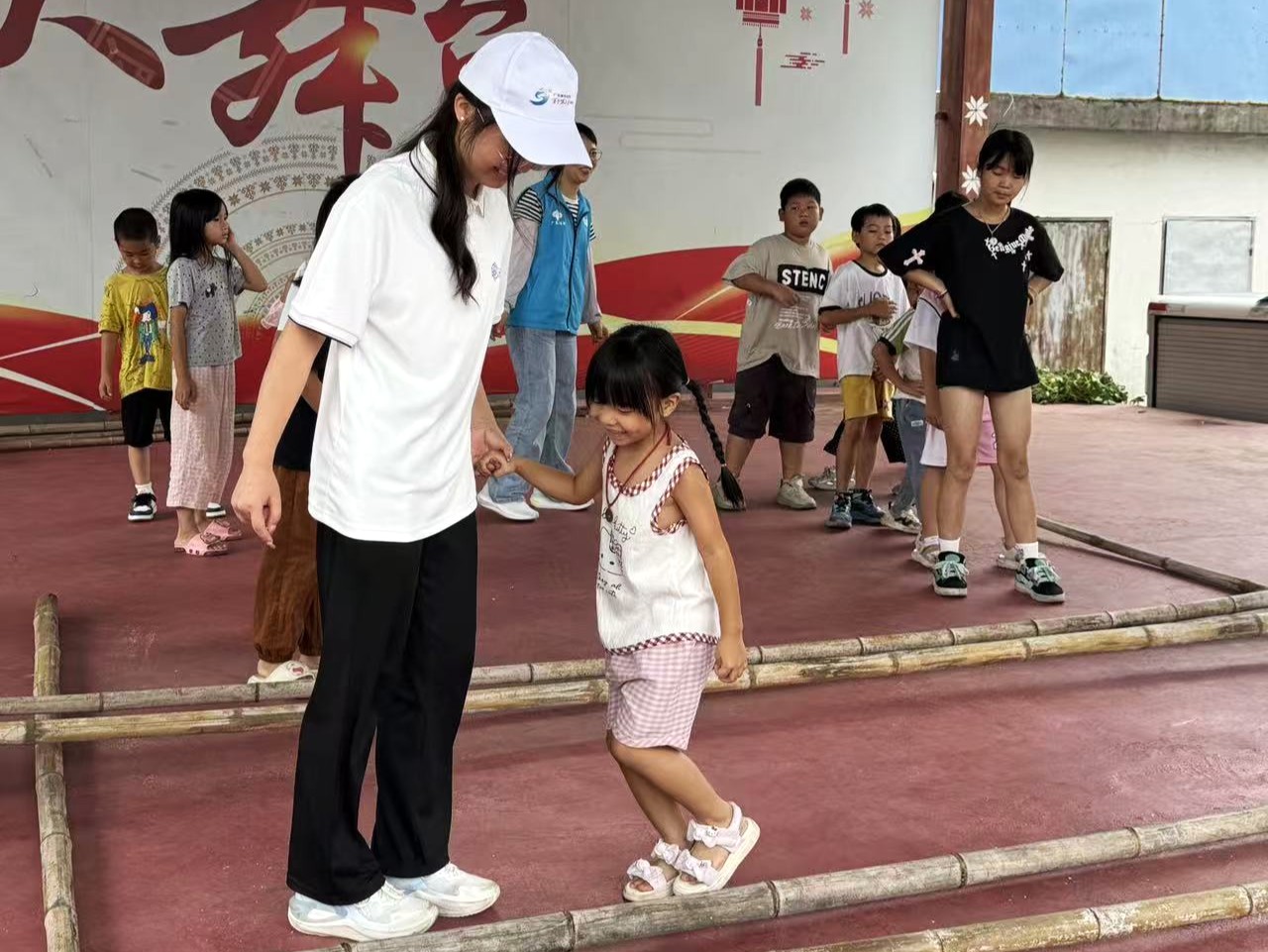 图为孩子们在队员陪伴下体验瑶族竹竿舞