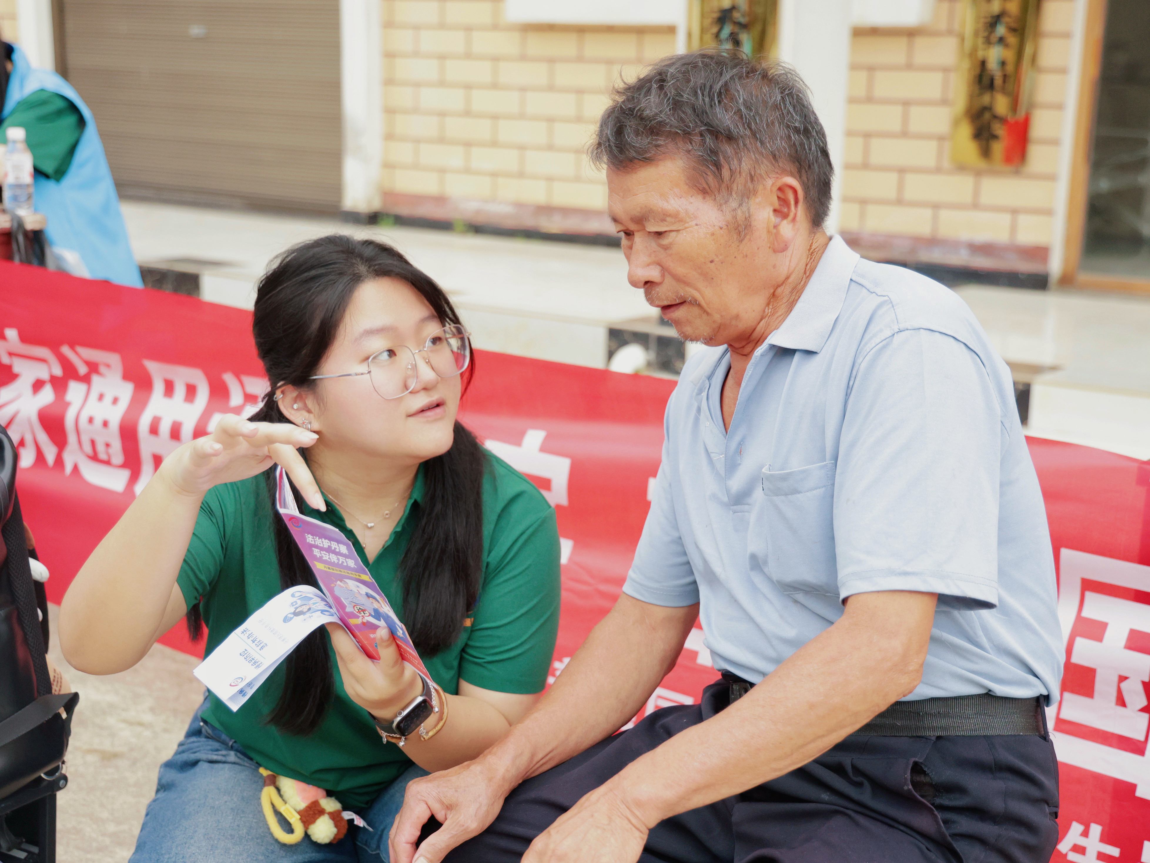 图为实践团成员在向展良村村民科普反诈骗.jpg