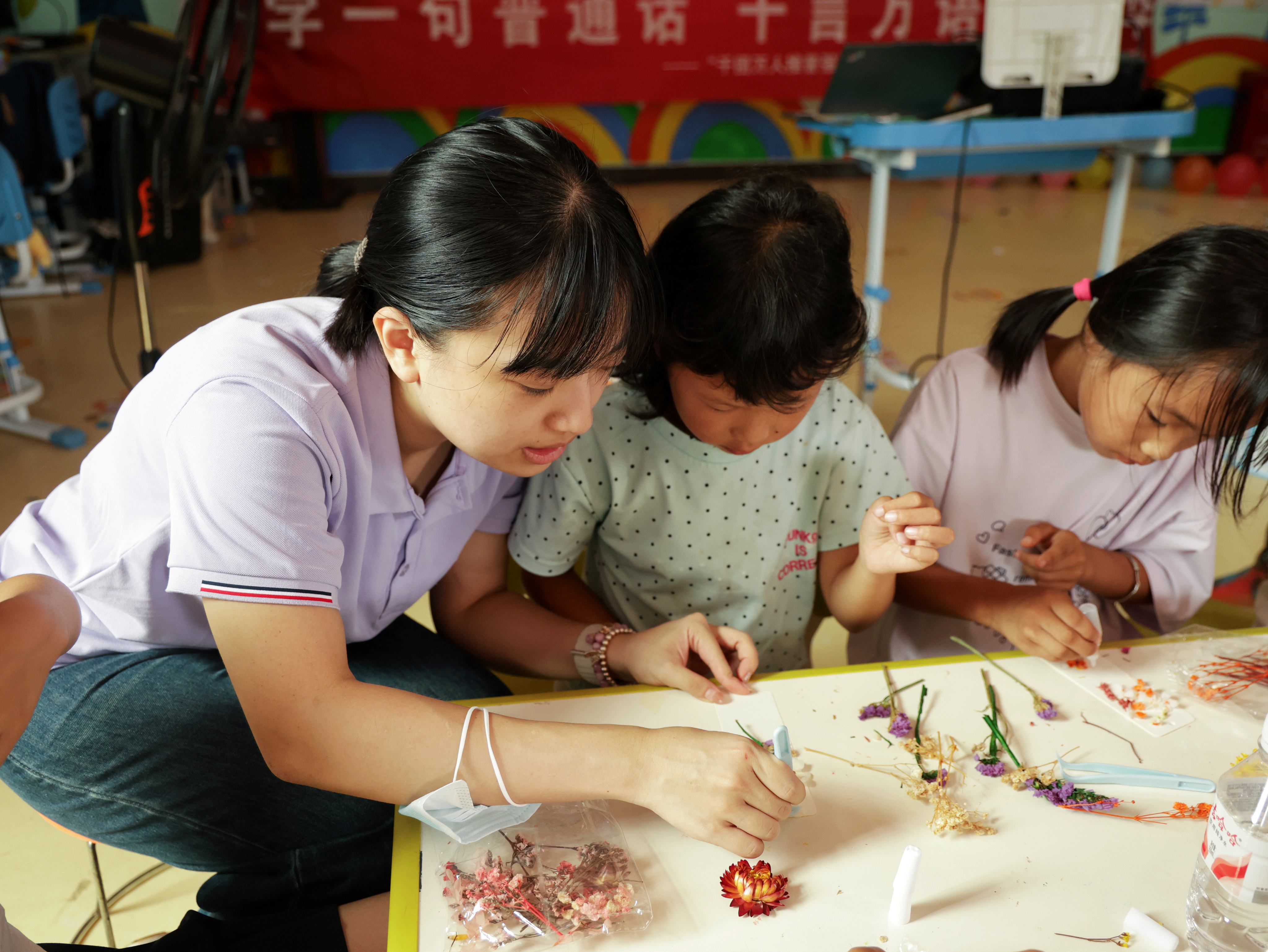 图为实践团成员在展良村的儿童之家和孩子们一起体验非遗押花.JPG