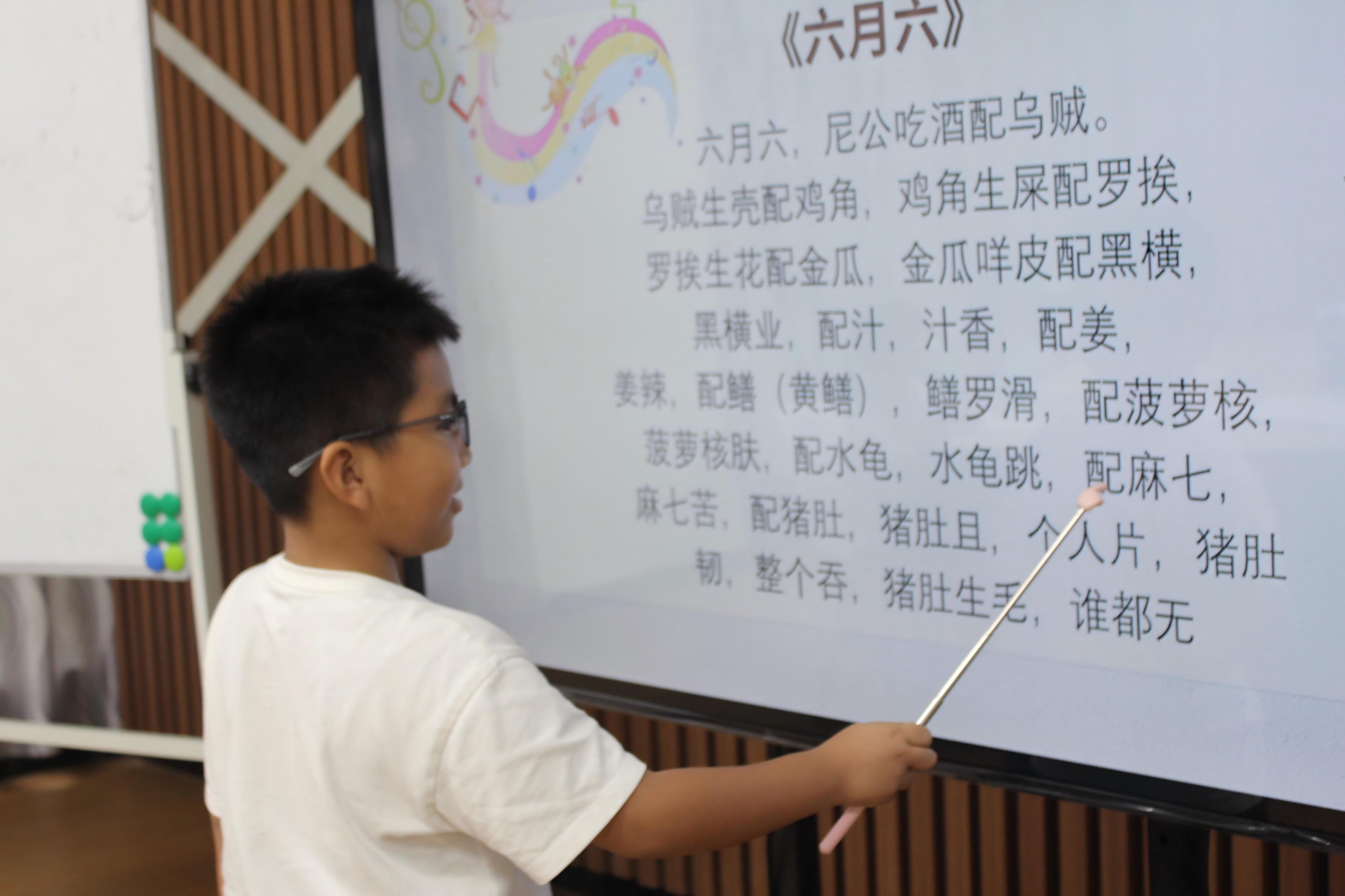 图7为小朋友指着设备屏幕诵读本土非遗童谣《六月六》