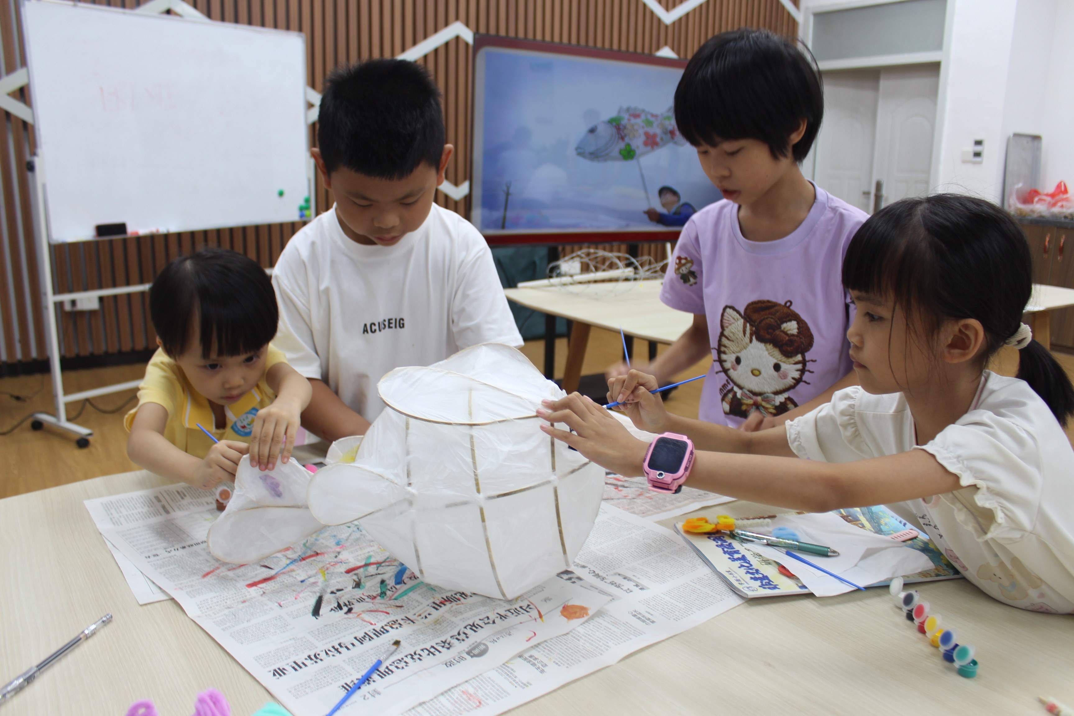 图8为孩子们协作动手绘制传统鱼灯，体验非遗手工制作